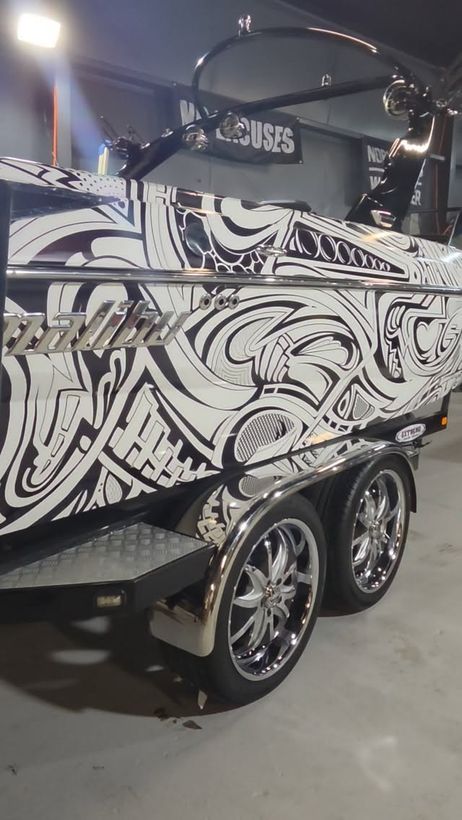 Black-and-white wrapped Malibu boat on its trailer in their shop